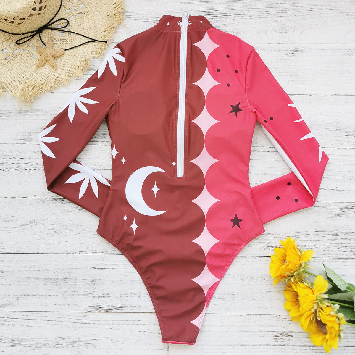 Vibrant pink and red long-sleeve swimsuit with bold sun and star patterns,perfect for a stylish beach look.