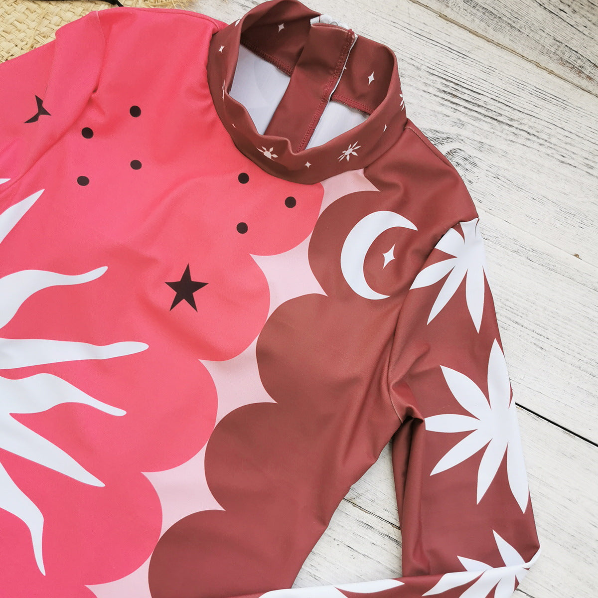 Vibrant pink and red long-sleeve swimsuit with bold sun and star patterns,perfect for a stylish beach look.