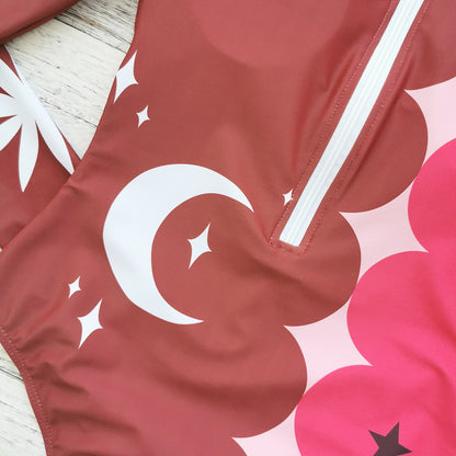 Vibrant pink and red long-sleeve swimsuit with bold sun and star patterns,perfect for a stylish beach look.
