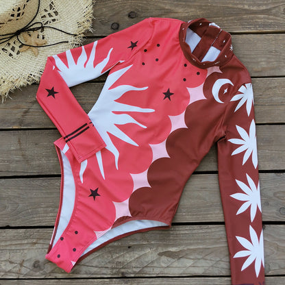 Vibrant pink and red long-sleeve swimsuit with bold sun and star patterns,perfect for a stylish beach look.