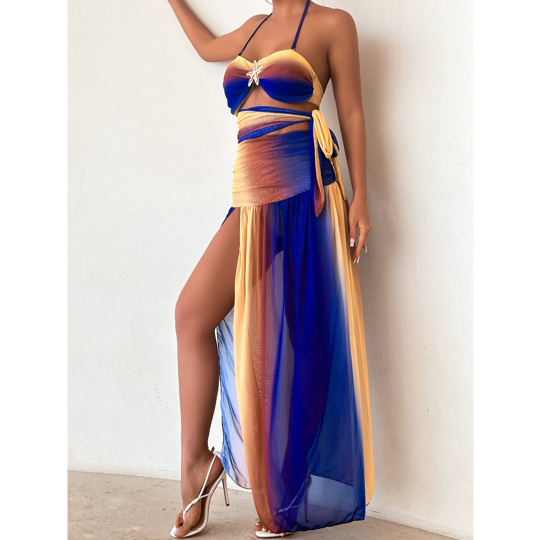 Woman wearing a colorful two-piece swimsuit with a long blue cover-up against a white background