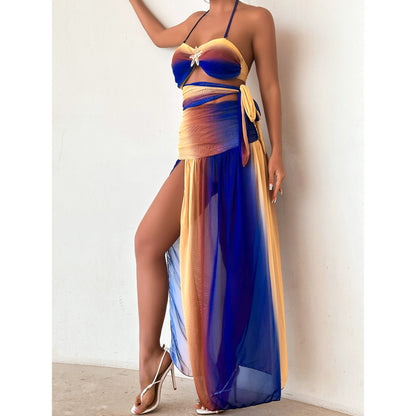 Woman wearing a colorful two-piece swimsuit with a long blue cover-up against a white background