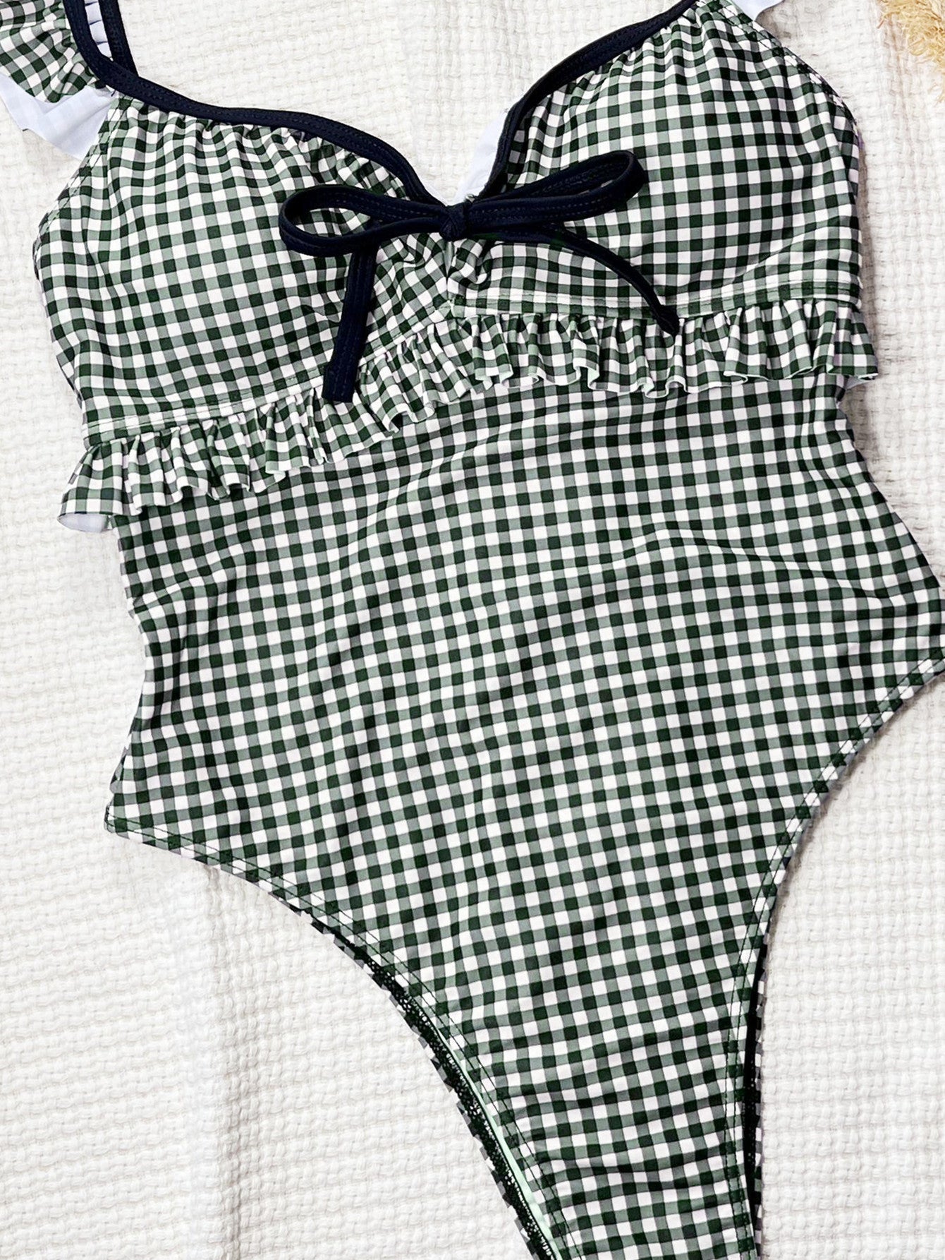 Black and white gingham one-piece swimsuit with ruffled straps.