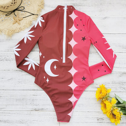 Vibrant pink and red long-sleeve swimsuit with bold sun and star patterns,perfect for a stylish beach look.
