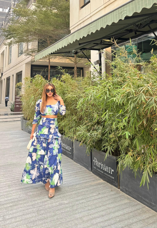 Stylish two-piece outfit consisting of a blue and white floral-print crop top with puff sleeves and a maching tiered maxi skirt.